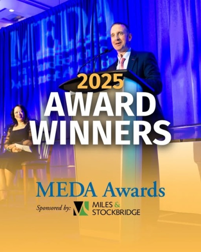 2025 Award Winners, MEDA Awards, Sponsored by Miles & Stockbridge; Photo: background of blue and yellow with a man standing at a podium